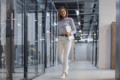 Businesswoman walking along the office corridor with documents.