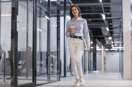 Free Download Businesswoman walking along the office corridor with paper cup. - GFXLoad