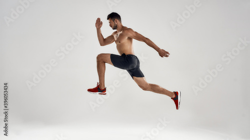 Young handsome caucasian male runner jumping high