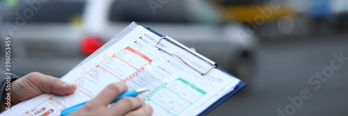 Man on street fills out an accident statement. Filling in by driver for subsequent transfer this information to insurance company. Accident reports on road. Keep calm during an accident on street