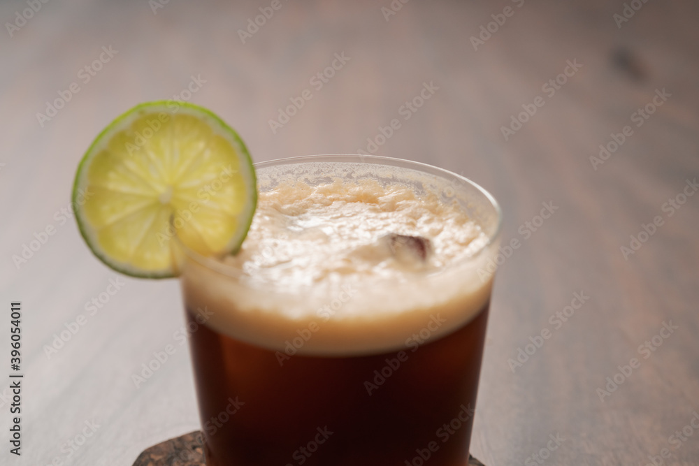 Espresso tonic in simple glass on walnut wood table with copy space