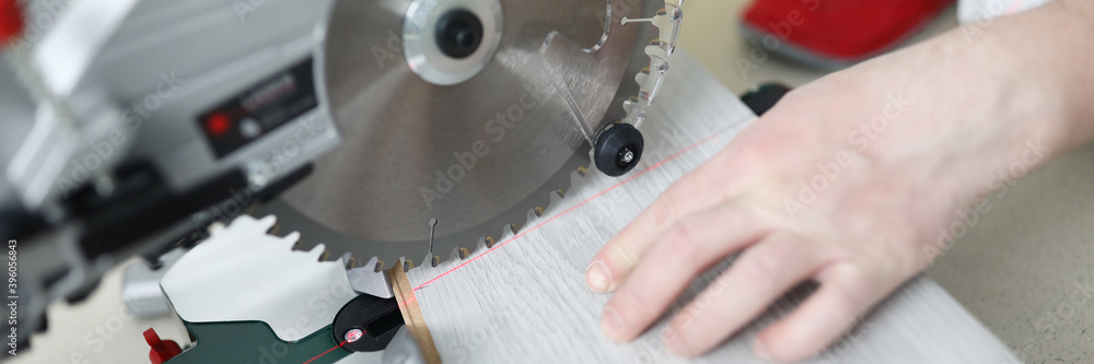 Man uses circular saw table while cutting laminate. Laminate laying technology with Click lock. Features of sawing laminate. Flooring option. Imitation shades and textures various types wood Man uses circular saw table while cutting laminate. Laminate laying technology with Click lock. Features of sawing laminate. Flooring option. Imitation shades and textures various types wood