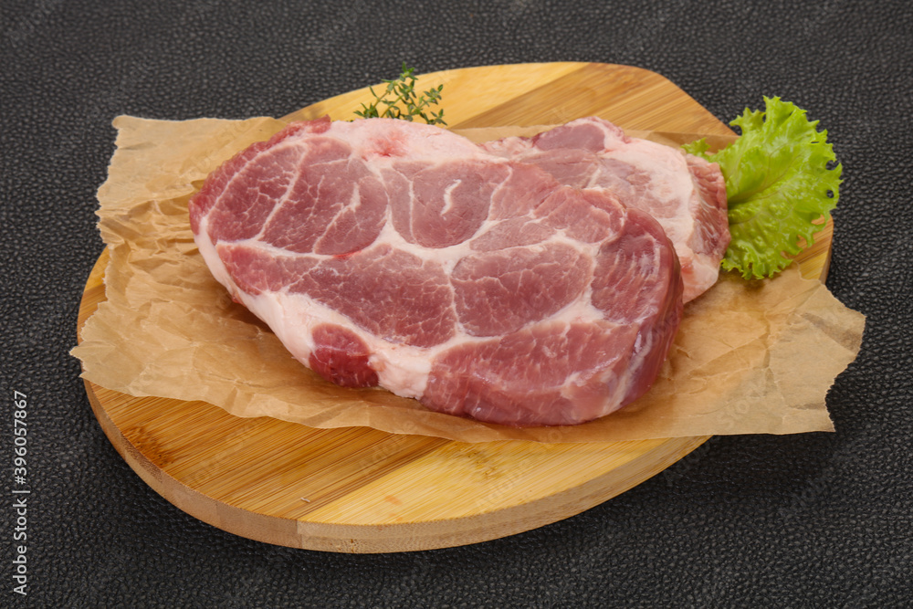 Raw pork steak over wooden board Raw pork steak over wooden board