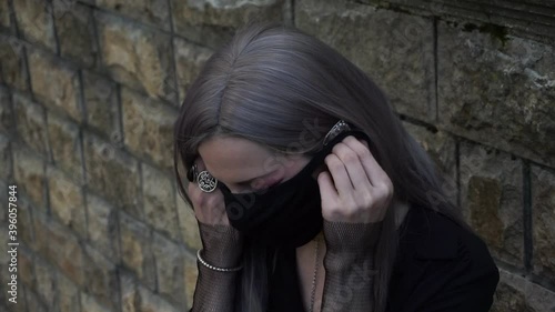 Cosplay girl puts on a black mask on her face