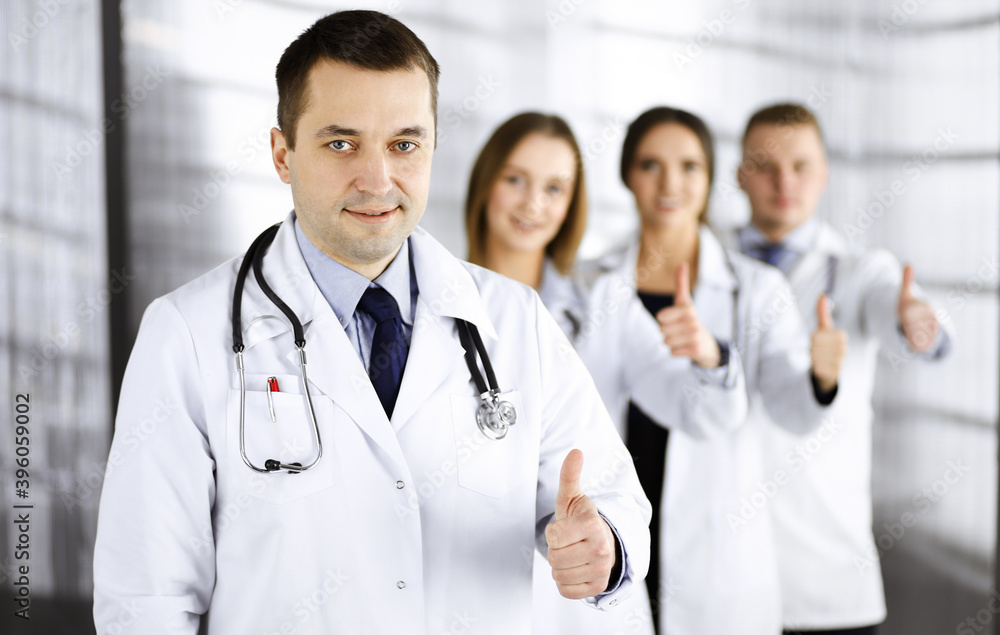 Group of professional doctors are standing as a team with thumbs up in a hospital office, ready to help their patients. Medical help, insurance in health care and medicine concept Group of professional doctors are standing as a team with thumbs up in a hospital office, ready to help their patients. Medical help, insurance in health care and medicine concept
