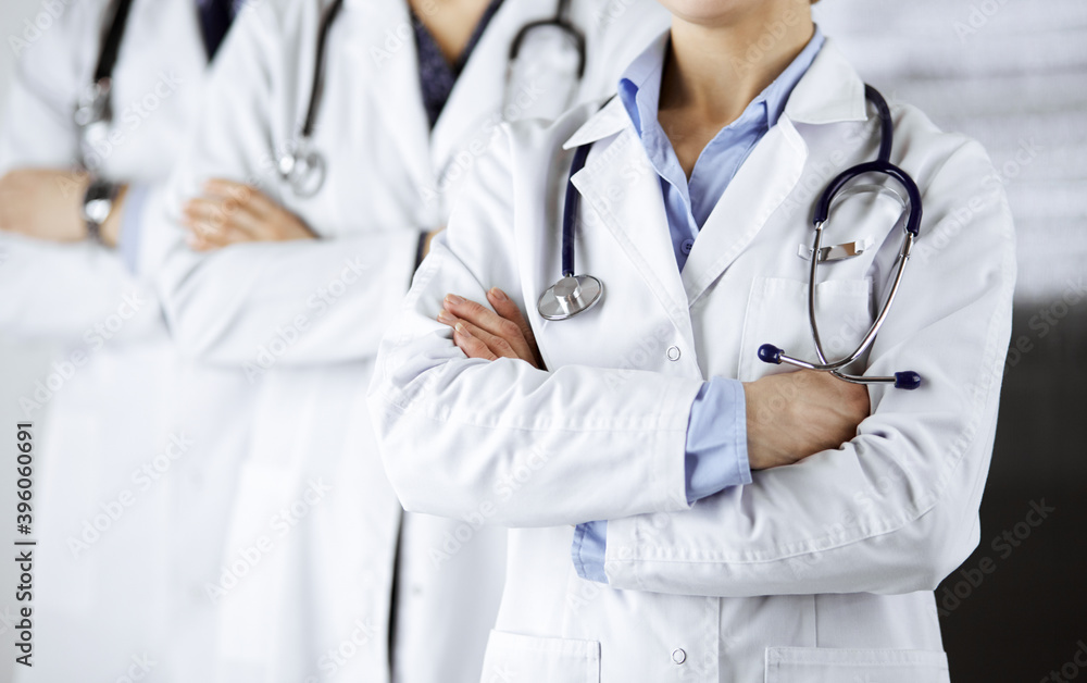 Group of modern doctors standing as a team with arms crossed in hospital office and ready to help patients. Medical help, insurance in health care, best disease treatment and medicine concept Group of modern doctors standing as a team with arms crossed in hospital office and ready to help patients. Medical help, insurance in health care, best disease treatment and medicine concept