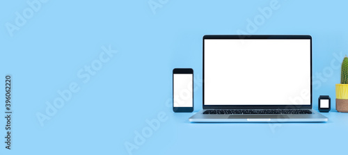Mockup image computer, smart watch, cell phone with blank screen for typing text in workplace on desk at office. Conception design creative work space on blue background. Modern digital devices