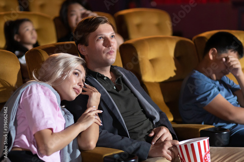 Young woman with friends watching movie in cinema . diversity people watching movie in cinema theater with popcorn and drinks.