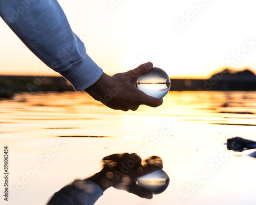 Person holding a Lens ball beside the water