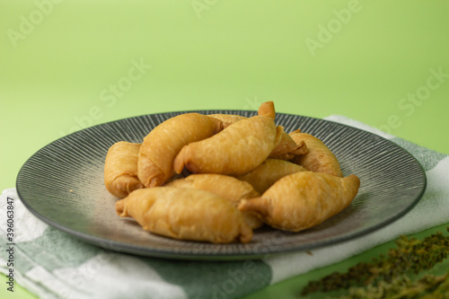 Pisang Molen, Indonesian traditional street food, made from banana fruits stuffed with pastry dought and cooked with deep fry step.Served on grey ceramic plate,  Isolated green background. photo