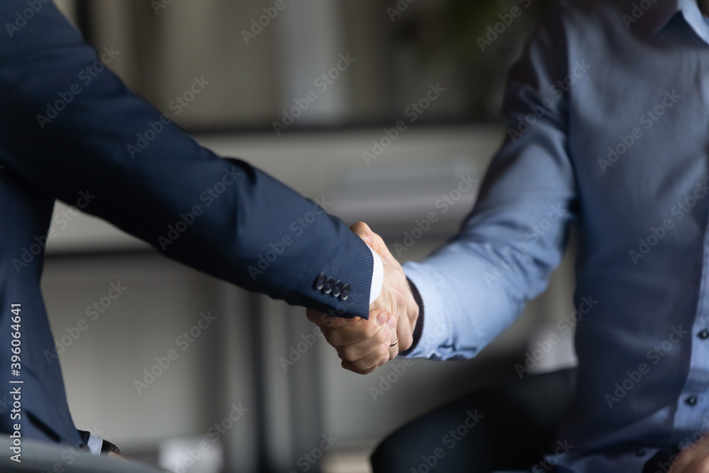 Firm handshake. Close up of two businessmen in formal suits shaking hands in office closing deal after successful negotiations, hr boss hiring new employee, team leader showing respect to staff member - obrazy, fototapety, plakaty 