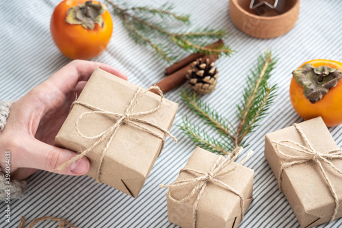 Girl holding a gift Packed with her own hands, close-up. Christmas decoration, design of a gift box for Christmas made of natural materials. New year's atmosphere, preparation for Christmas