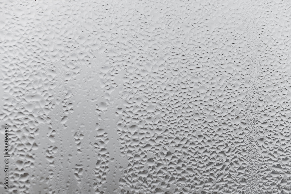Natural drops of water flow down the glass, high humidity in the room, condensation on the glass window. Neutral colors. Excellent background with condensation drops texture Natural drops of water flow down the glass, high humidity in the room, condensation on the glass window. Neutral colors. Excellent background with condensation drops texture