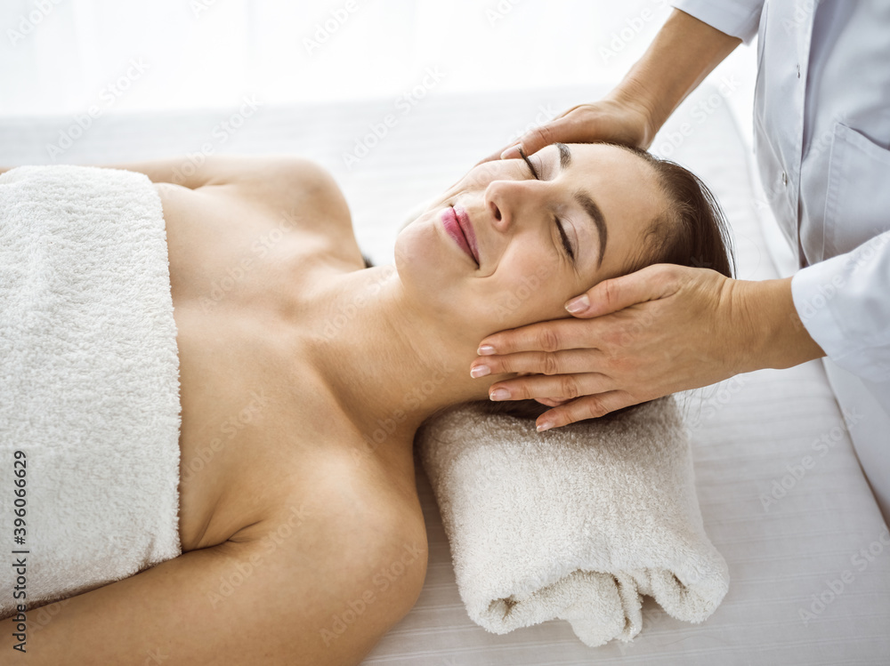 Beautiful brunette woman enjoying facial massage comfortable and bissfulle. Relaxing treatment in medicine and spa center concepts