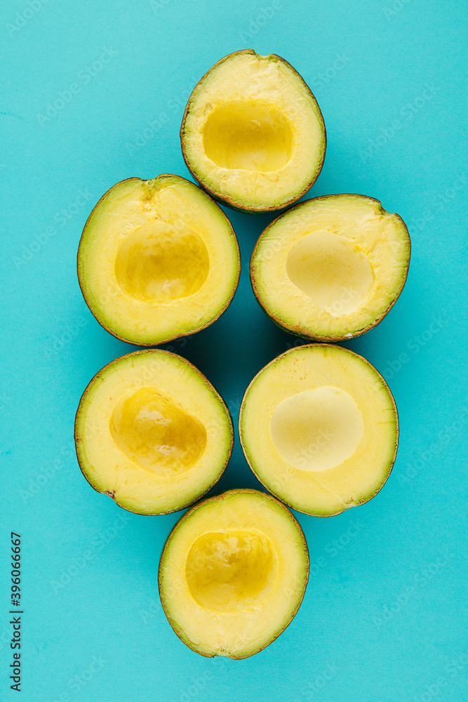 Halves of avocados without pits on light blue background Halves of avocados without pits on light blue background