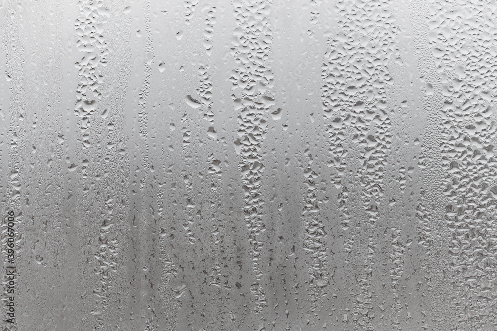 Close up water drop on grey background, misted glass with droplets of water draining down. Dripping Condensation Close up water drop on grey background, misted glass with droplets of water draining down. Dripping Condensation