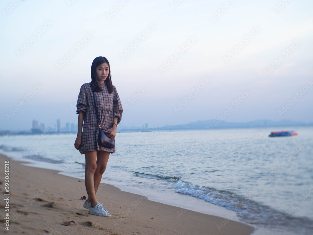 A woman in a striped shirt is standing by the sandy beach.