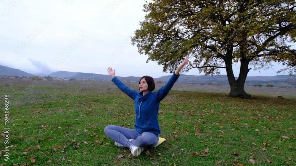 Young athletic asian woman meditating in the field by old oak, zen yoga meditation practice in nature Young athletic asian woman meditating in the field by old oak, zen yoga meditation practice in nature