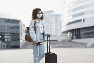 Young woman tourist holding passport and ticket, girl wearing protective face mask in a city, Business travel during pandemic, corona virus protection, healthy lifestyle, people, tourism concept