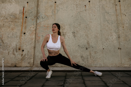 Outdoor portrait of young woman do exercise and stretching. Lifestyle concept.