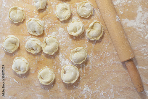 Closeup on semi-finished pelmeni dumplings on the wooden board.