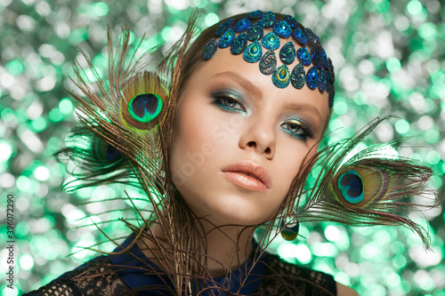 Beautiful fashion woman face. Woman in peacock image with peacock feathers.
