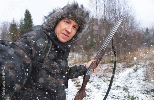 Hunter with a gun takes a selfie in the winter forest 