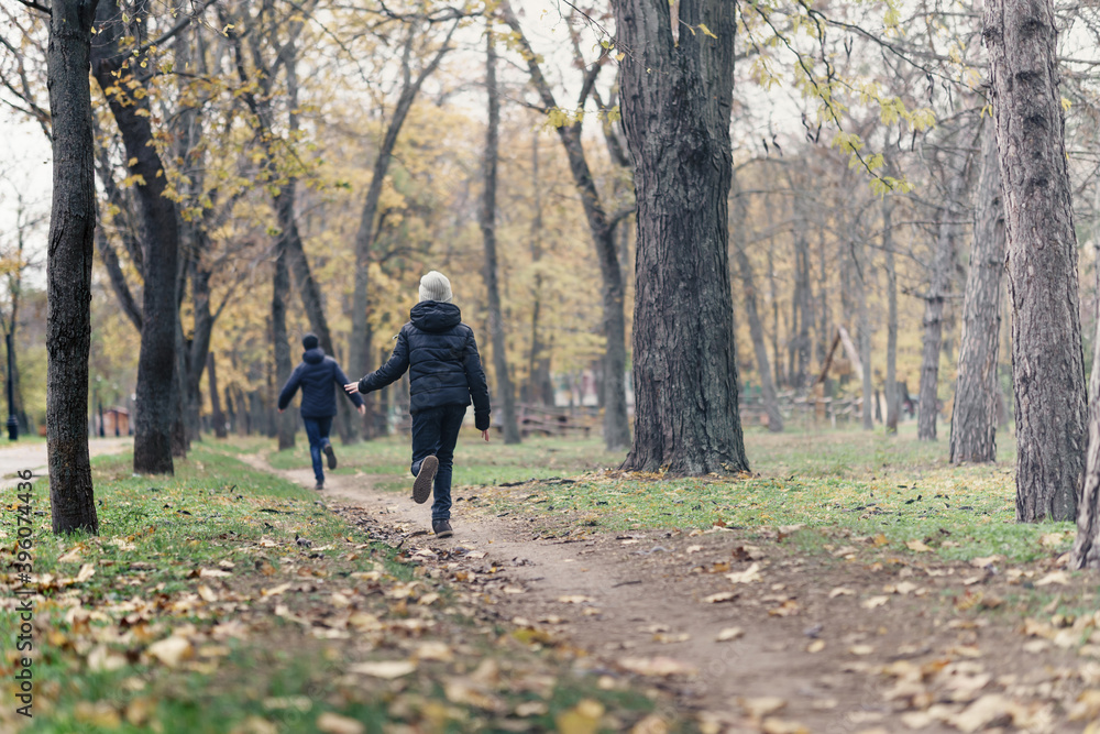 teen girl and boy running through the park and enjoys autumn, beautiful nature with yellow leaves teen girl and boy running through the park and enjoys autumn, beautiful nature with yellow leaves