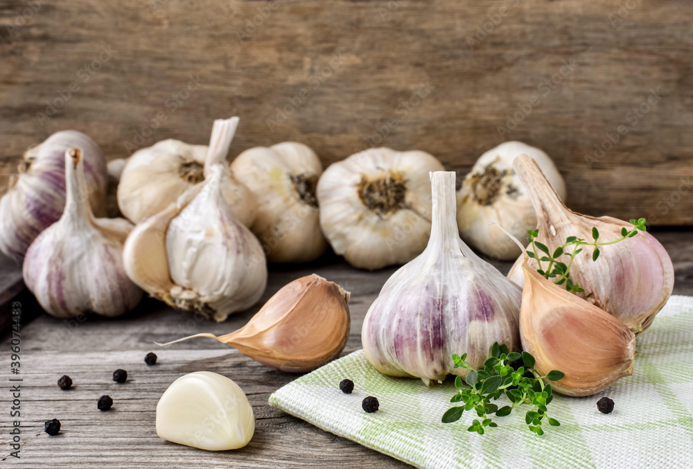 Garlic on a wooden, rustic table, a branch of thyme and black peppercorns. A bunch of fresh garlic, peeled cloves. Garlic on a wooden, rustic table, a branch of thyme and black peppercorns. A bunch of fresh garlic, peeled cloves.