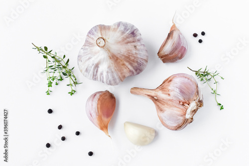 Garlic, aromatic herb thyme and black peppercorns on a white background. Top view, close-up.
