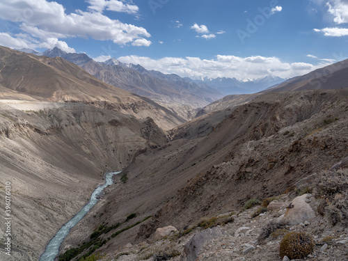 Landscape view of Pamir river valley in altitude desert between Afghanistan and Tajikistan in Wakhan Corridor with Hindu Kush mountain range in background, Gorno-Badakshan 