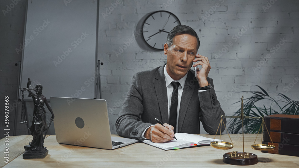 agent talking on smartphone near laptop, notebook and scales on table in office agent talking on smartphone near laptop, notebook and scales on table in office