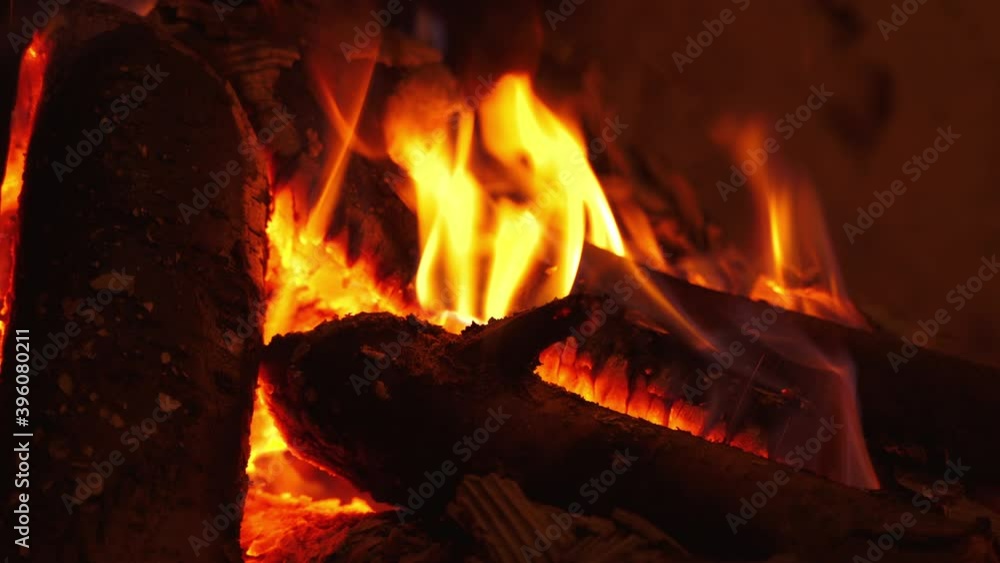 Romantic fireplace. Smoldering logs in hot flame burning in fireplace at home. Motion of fire in wood indoors. Close-up. Romantic fireplace. Smoldering logs in hot flame burning in fireplace at home. Motion of fire in wood indoors. Close-up.