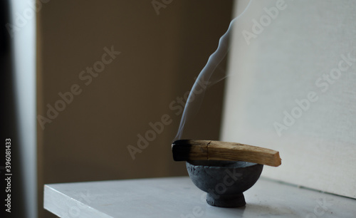 Φωτογραφία An image of a burning palo santo smudge stick in a stone bowl on a white ledge