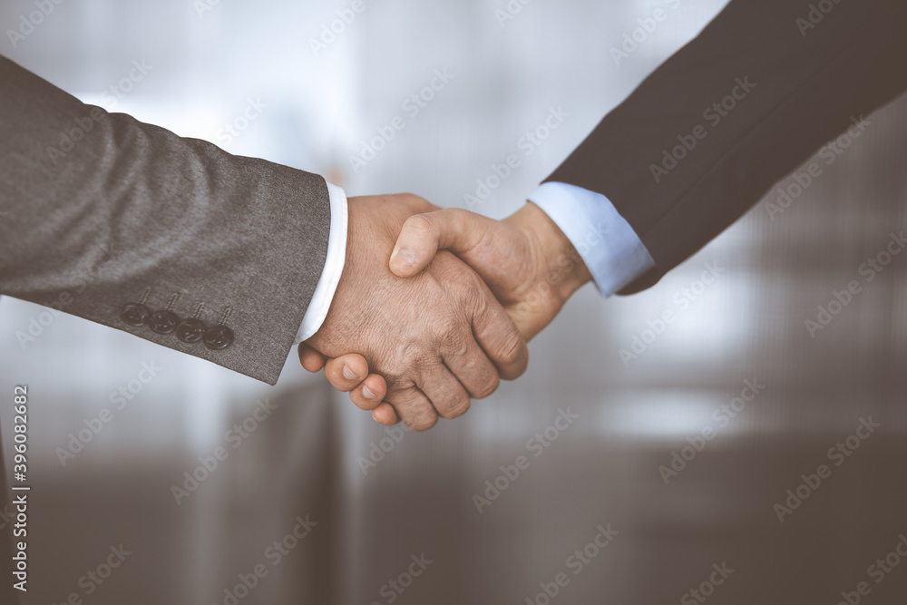 Business people in office suits standing and shaking hands, close-up. Business communication concept. Handshake and marketing Business people in office suits standing and shaking hands, close-up. Business communication concept. Handshake and marketing