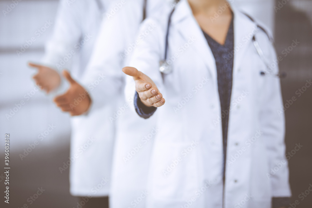 Doctors standing as a team while offering helping hand for shaking hand or saving life in clinic