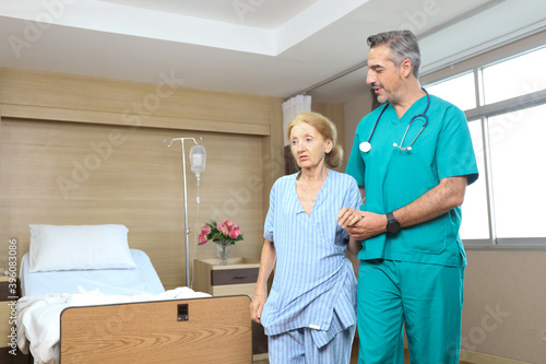Doctor or assistance staff talking and support an elder patient woman while try to walking in the hospital