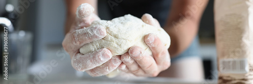 Fotografi Male hands knead the dough in flour. Homemade cooking concept