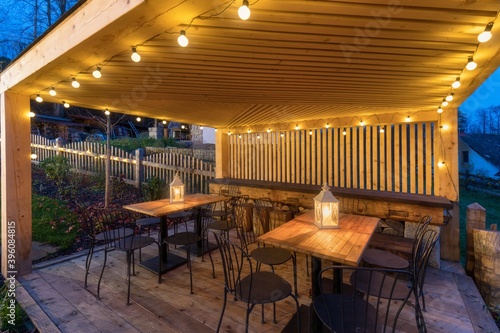 gazebo with lights/gazebo at night/a gazebo lit up at night 
Picture of a summer house with comfortable garden furniture. Romantic scene in dusk.