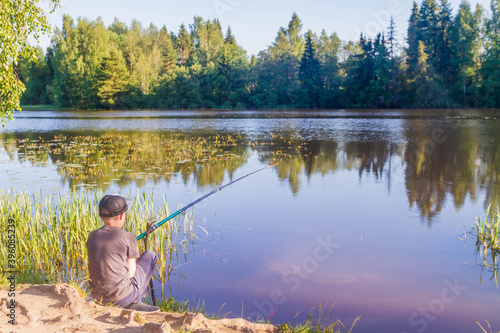 A teenage European boy fishing with a fishing rod in the summer. Fishing on the river in Russia.