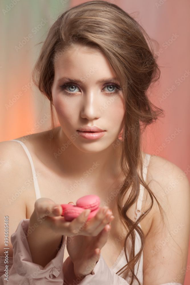 Beauty fashion model woman with delicate makeup and manicure taking pink macaroons Beauty fashion model woman with delicate makeup and manicure taking pink macaroons