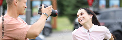Male photographer with camera photographs smiling woman. Professional services photographer concept