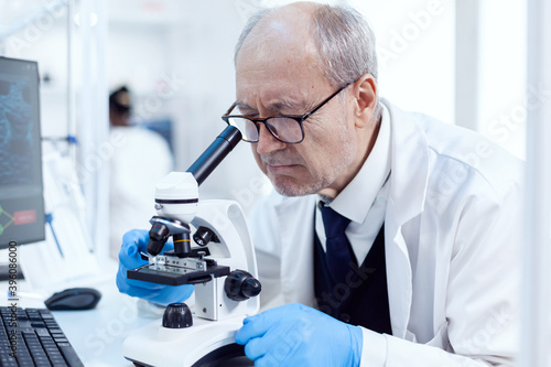 Senior scientist working on busy laboratory using modern microscope with slides. Chemist researcher in sterile lab doing experiments for medical industry using modern technology.