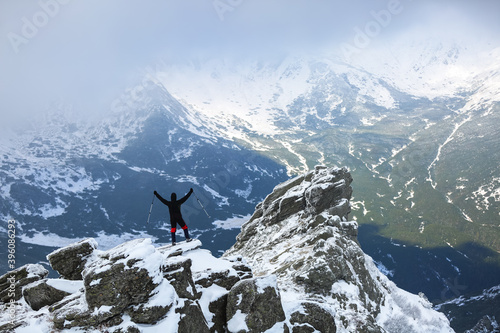 Landscape on the cold winter day . Happy tourist is standing at the edge of the precipice. High mountains with snow white peaks. Snowy background. Location place the Carpathian, Ukraine, Europe. © Vitalii_Mamchuk