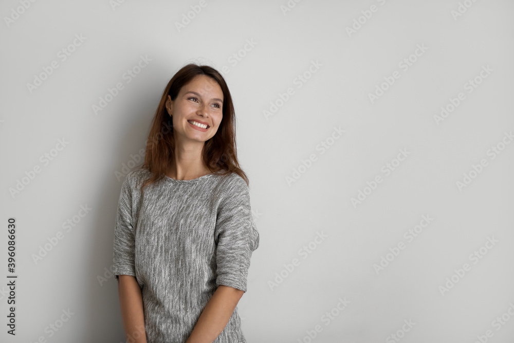 Dreamy smiling young beautiful woman looking in distance, thinking of new challenges or opportunities, showing positive good mood, isolated on grey white studio background copy space for ad text. Dreamy smiling young beautiful woman looking in distance, thinking of new challenges or opportunities, showing positive good mood, isolated on grey white studio background copy space for ad text.