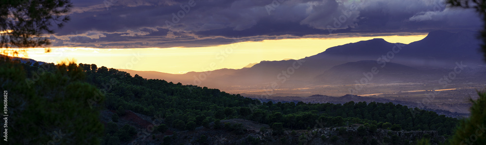 panoramic photo of a sunset in the mountains with rays of light