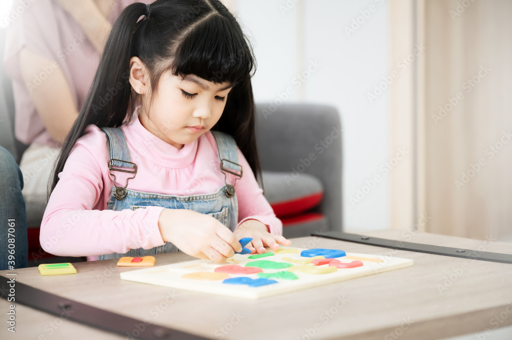 Asian daughter with parent playing toy puzzle on table at home. Kid girl is smiling and enjoy activity leisure Asian daughter with parent playing toy puzzle on table at home. Kid girl is smiling and enjoy activity leisure