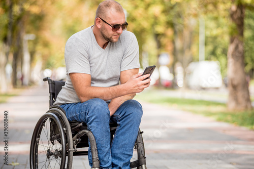 Handicapped man in wheelchair at the park alley use a smartphone © romaset