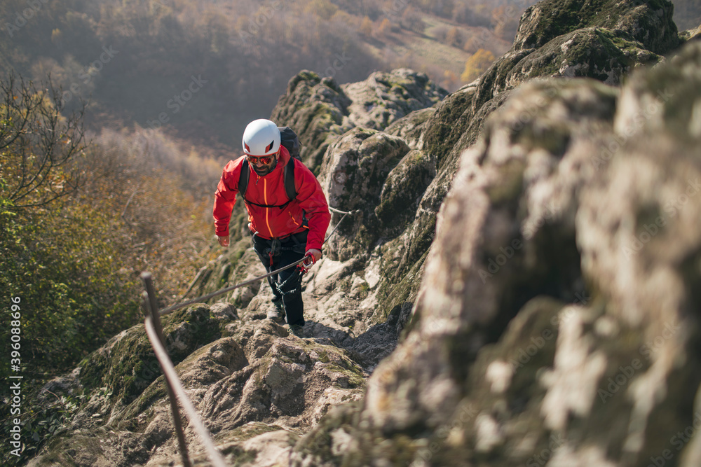 Obraz premium Fully equipped man climbing along a via ferrata, copy space