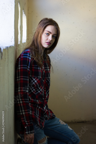 portrait of a young woman in shirt and jeans. Girl with blue eyes and red lips